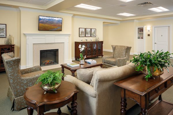 A cozy living room with a fireplace, adorned with comfortable furniture and green plants.