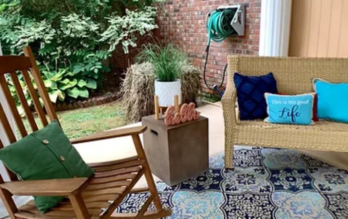 A cozy patio setup with outdoor seating, colorful cushions, and lush greenery.