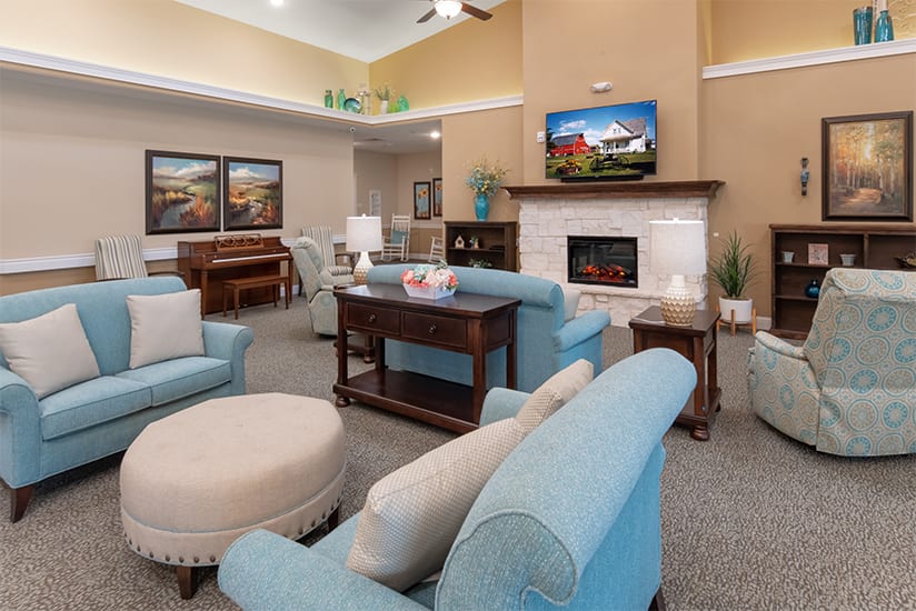 A cozy living room with blue sofas, a fireplace, and a television.