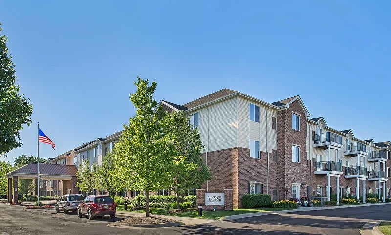 A residential apartment building with a clear blue sky and surrounding trees.