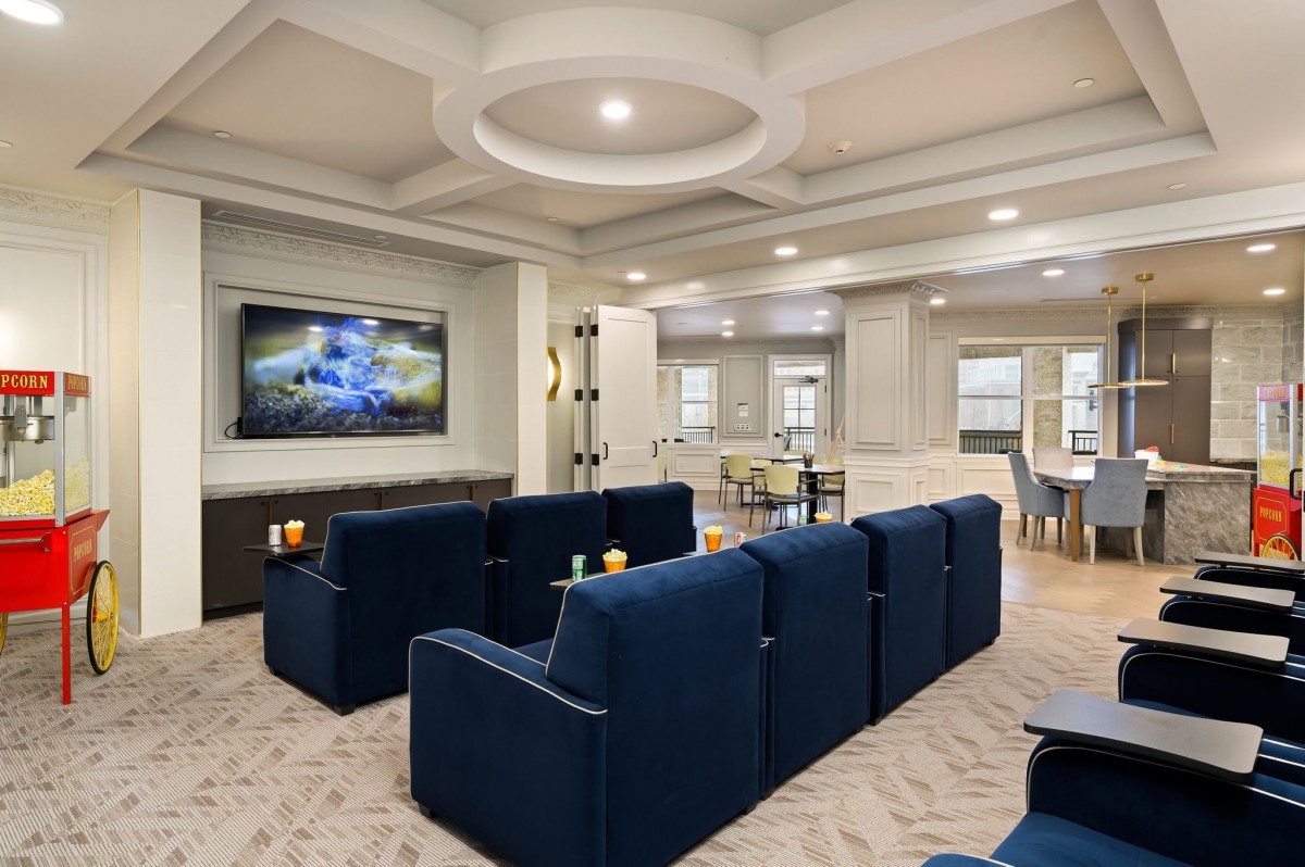 A modern living room with a home theater setup, featuring blue seating and a large television.