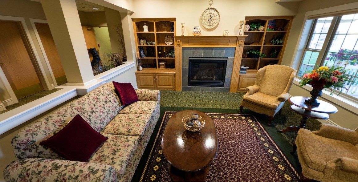 Cozy living room with a floral couch, fireplace, and bookshelves.