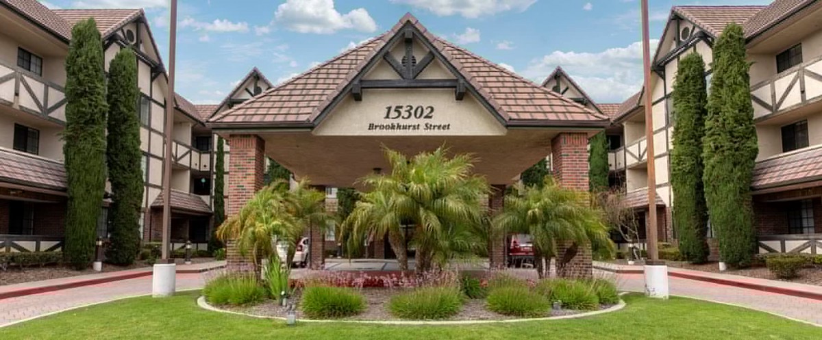 Entrance of a building with palm trees and an address sign.