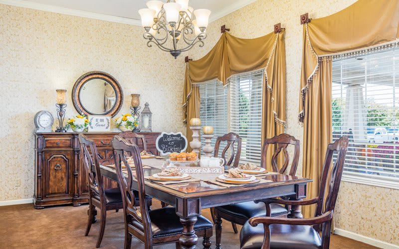 An elegant dining room with traditional wooden furniture, a formal table setting, and a chandelier.