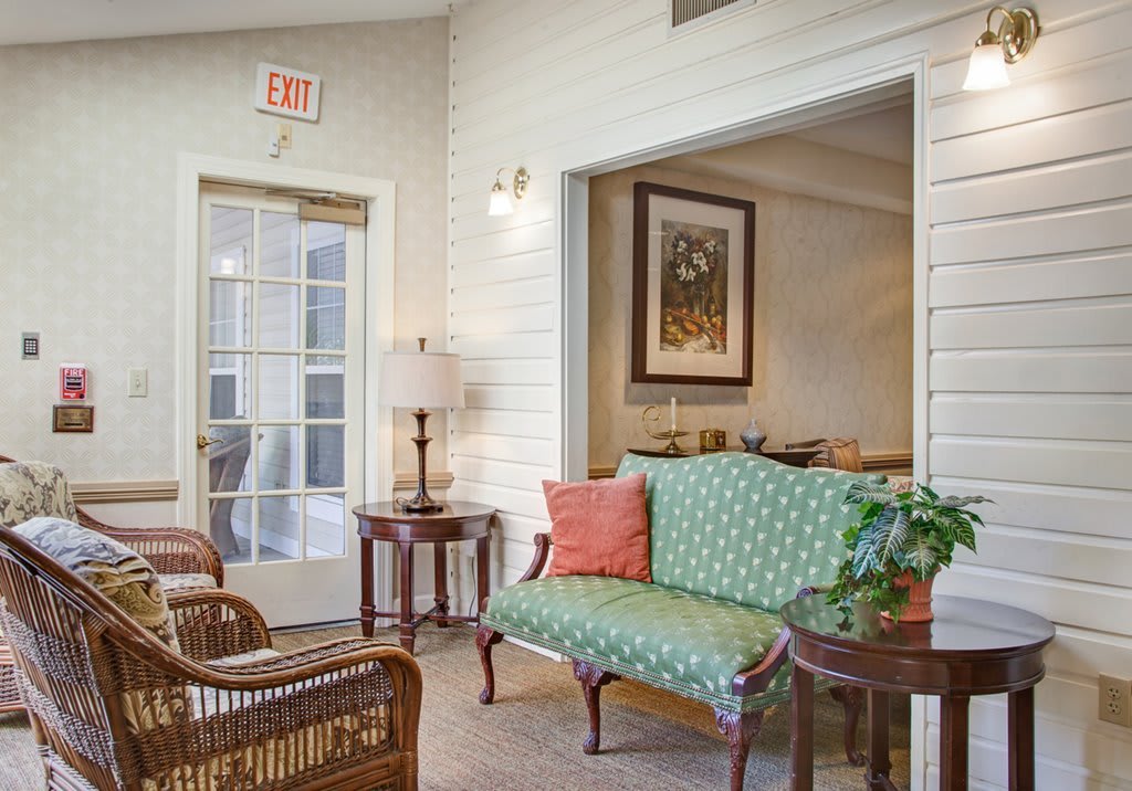 A cozy living room with a green sofa, wicker chairs, and decorative elements.