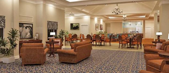 A spacious lobby with comfortable seating and a dining area in the background.