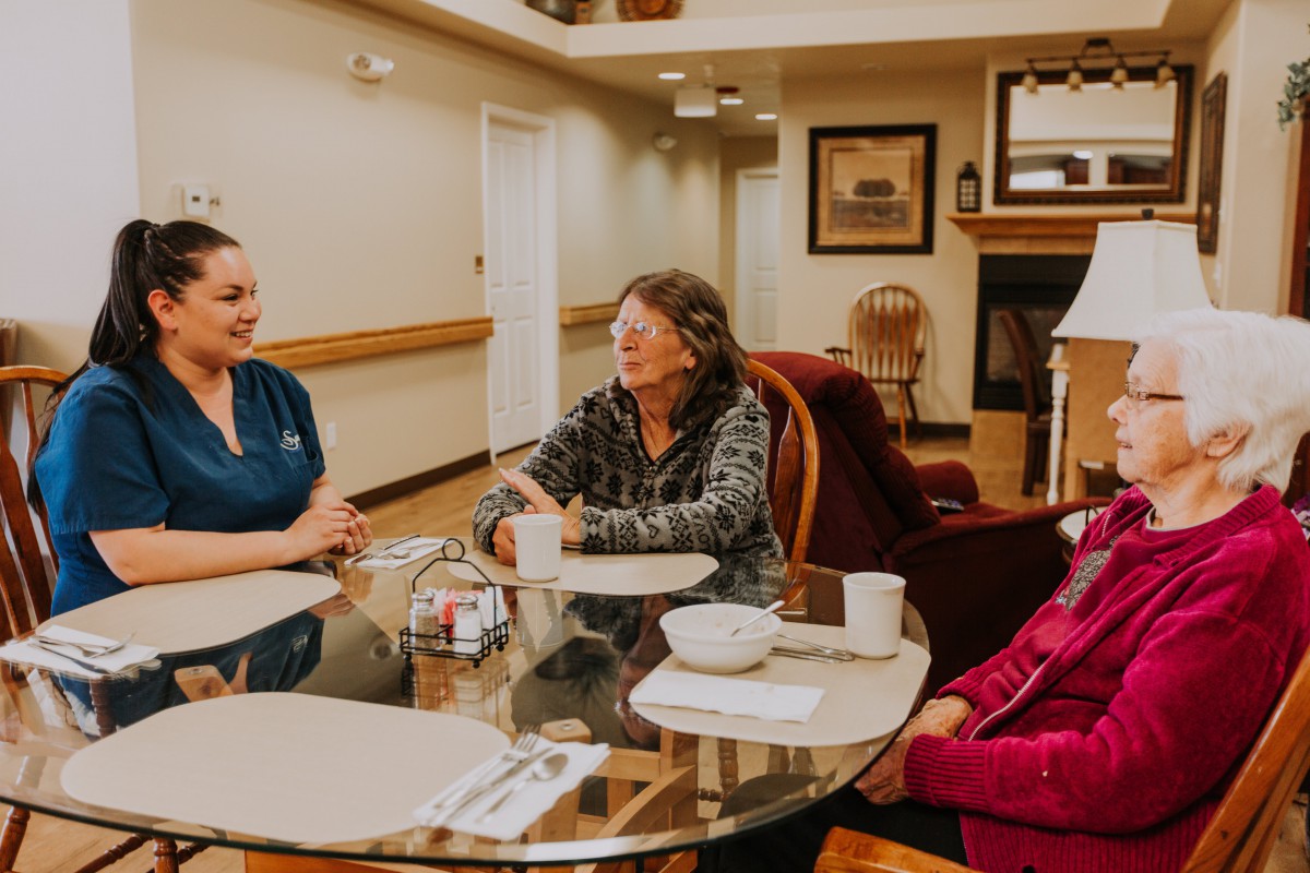 A group of people sitting at a table having a conversation in a care home setting.