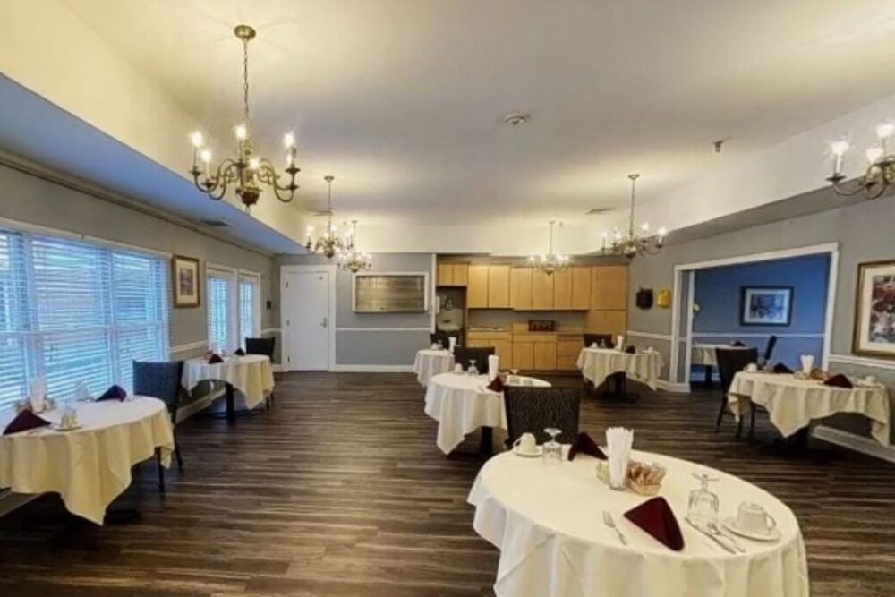 A well-appointed dining room with round tables, chandeliers, and wood flooring.