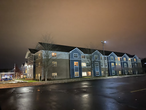 A modern apartment building illuminated at night with a wet street reflecting light.