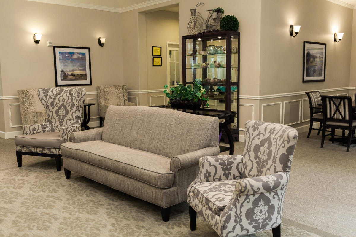 A cozy living room setup featuring a sofa, patterned armchairs, and a decorative cabinet.