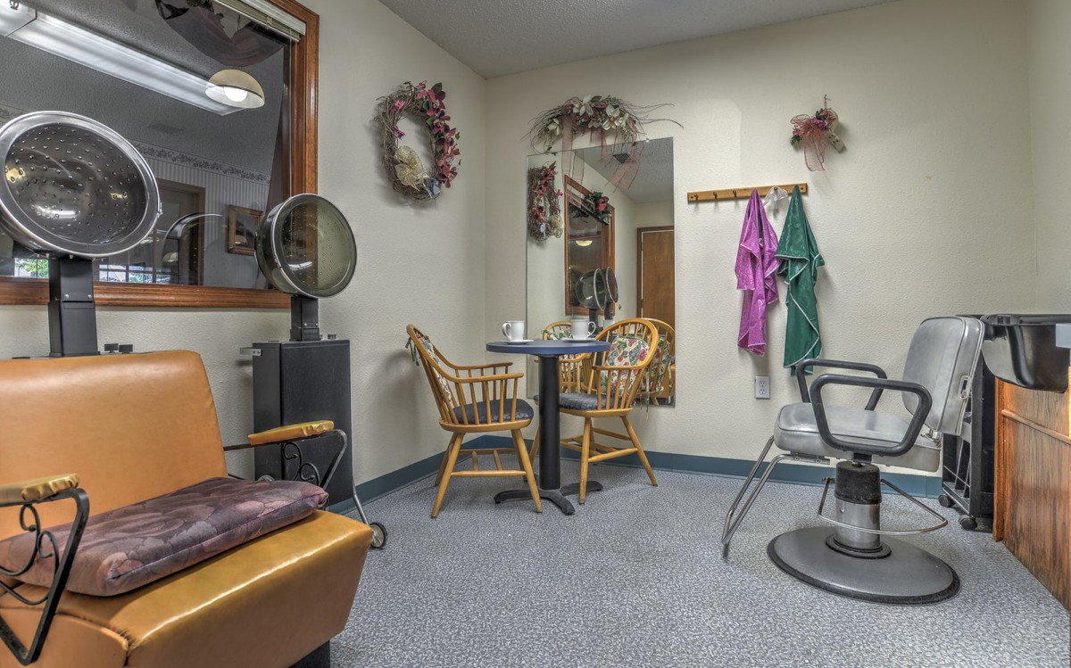 A cozy hair salon's waiting area with wicker chairs and decorative wall hangings.