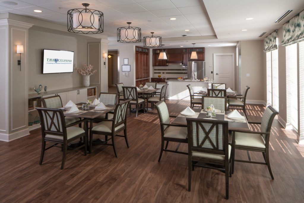 A modern dining room with neatly arranged tables and chairs, featuring elegant lighting fixtures.