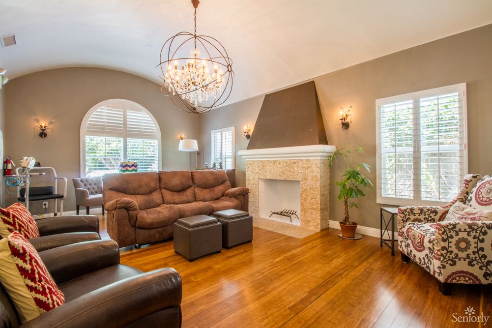 A cozy living room with a chandelier, comfortable seating, and a fireplace.