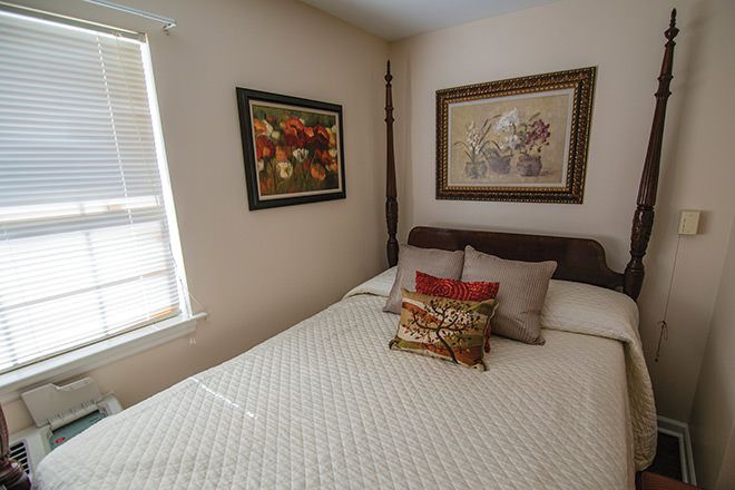 A cozy bedroom with wall art and decorative pillows, illuminated by natural light.