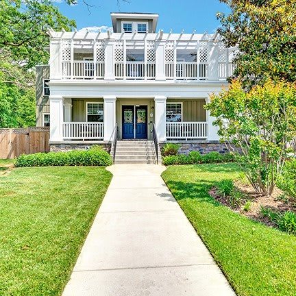 A beautiful two-story house with a large front yard and pathway leading to the entrance.