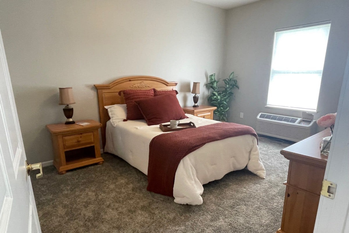 A cozy bedroom with a neatly made bed and warm decor.