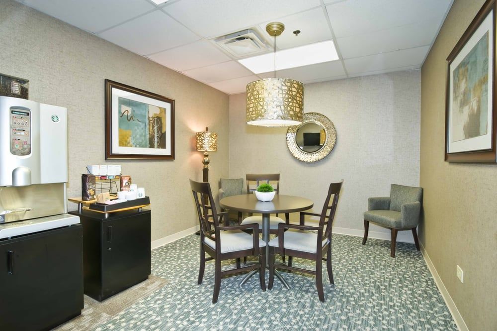 A modern office waiting area with a round table, chairs, and decorative elements.