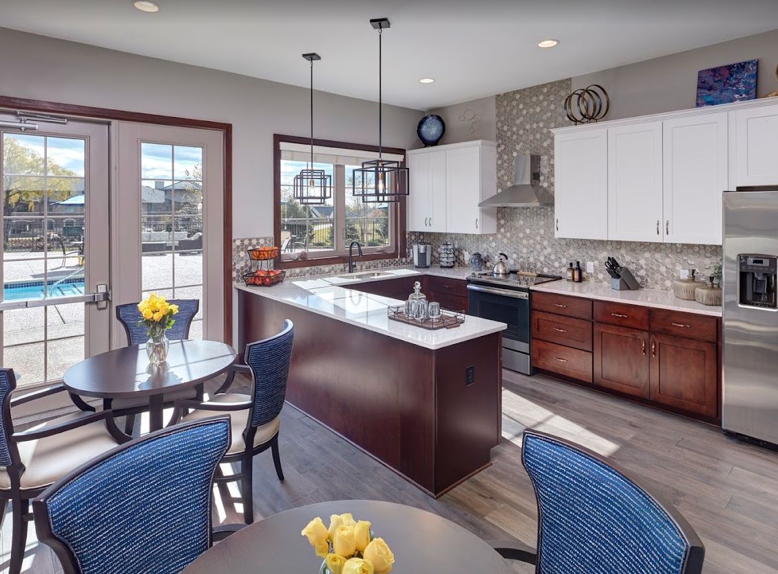 A modern kitchen with a central island and adjacent dining area, featuring pendant lighting and sleek cabinetry.