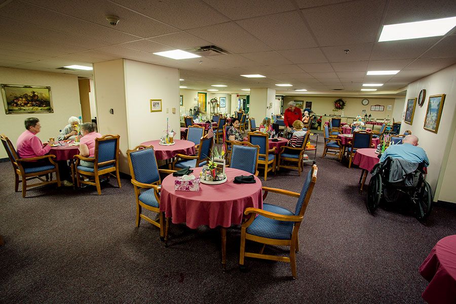 A cozy dining area with several round tables covered in pink tablecloths and wooden chairs arranged around them.