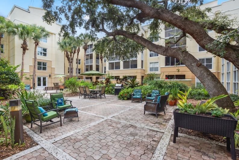 A well-maintained courtyard in an apartment complex featuring outdoor furniture and lush landscaping.