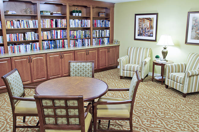 A cozy library corner with bookshelves, a round table, and comfortable seating.