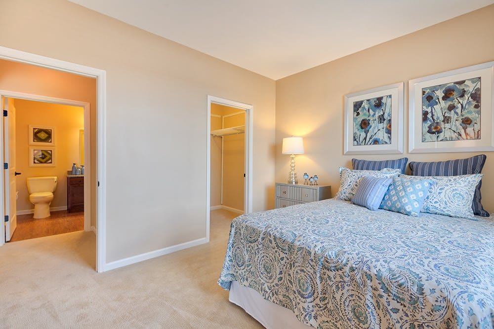 A cozy and elegantly decorated bedroom with a bed, bedside table, and framed artwork.