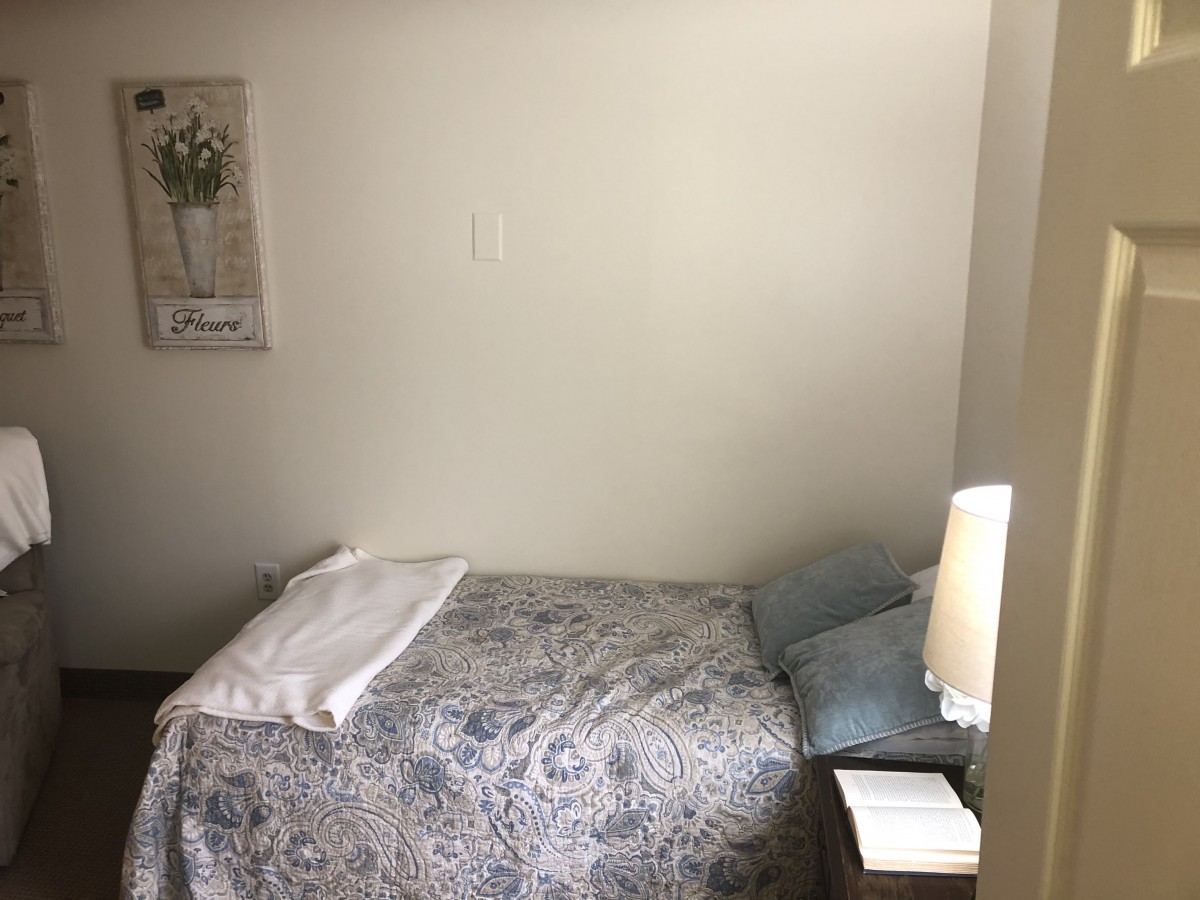A cozy bedroom with a neatly made bed, complete with pillows and a patterned blanket, accompanied by a bedside lamp.