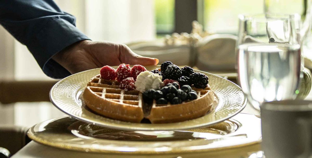 A delicious waffle topped with fresh berries and a dollop of cream served on a plate.