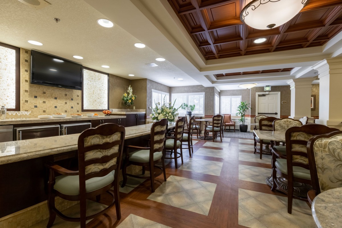 A spacious and elegantly designed dining area with wooden chairs and a polished floor, featuring warm lighting and tasteful decor.