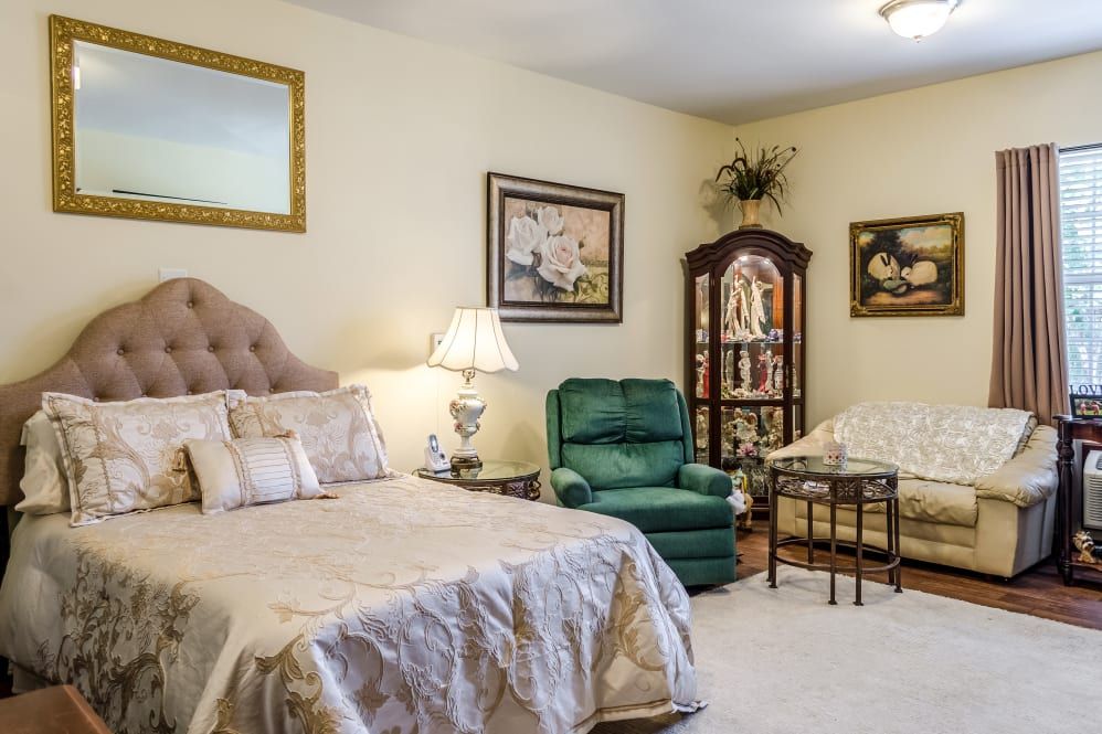 A cozy bedroom with elegant furnishings, including a bed, armchair, and decorative cabinet.