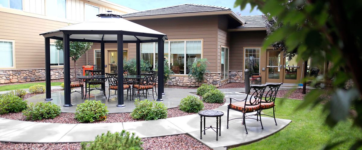 A well-maintained patio area featuring a gazebo, outdoor furniture, and surrounding landscaping.