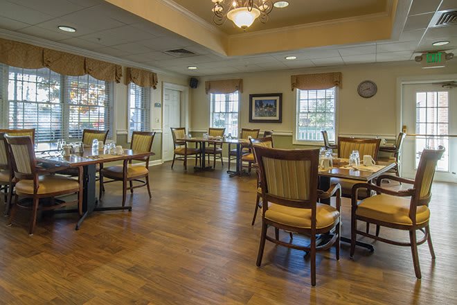 An elegant dining area with wooden floors and neatly arranged tables and chairs.