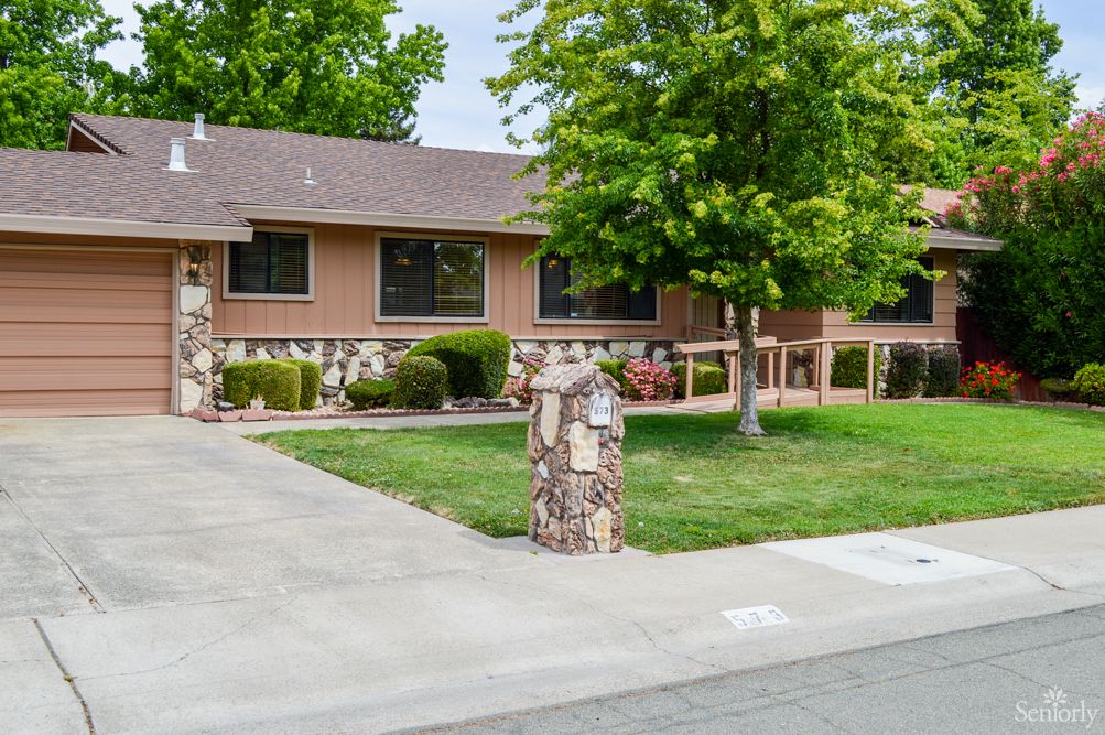 A suburban house with a well-kept yard and a tree in the front.