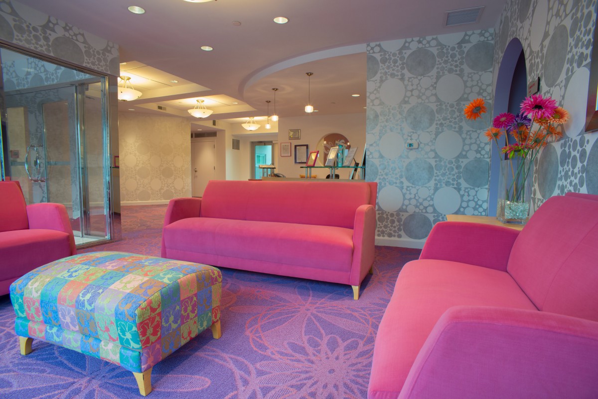 A vibrant lobby interior featuring pink sofas and a floral patterned carpet.
