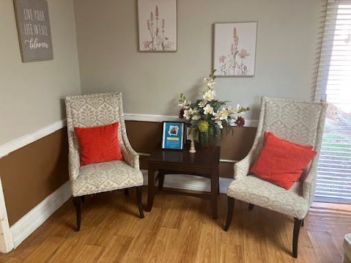 A cozy corner featuring elegant chairs, a decorative table with flowers, and artwork on the walls.