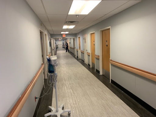 A quiet corridor in a hospital, featuring lined doors and medical equipment.