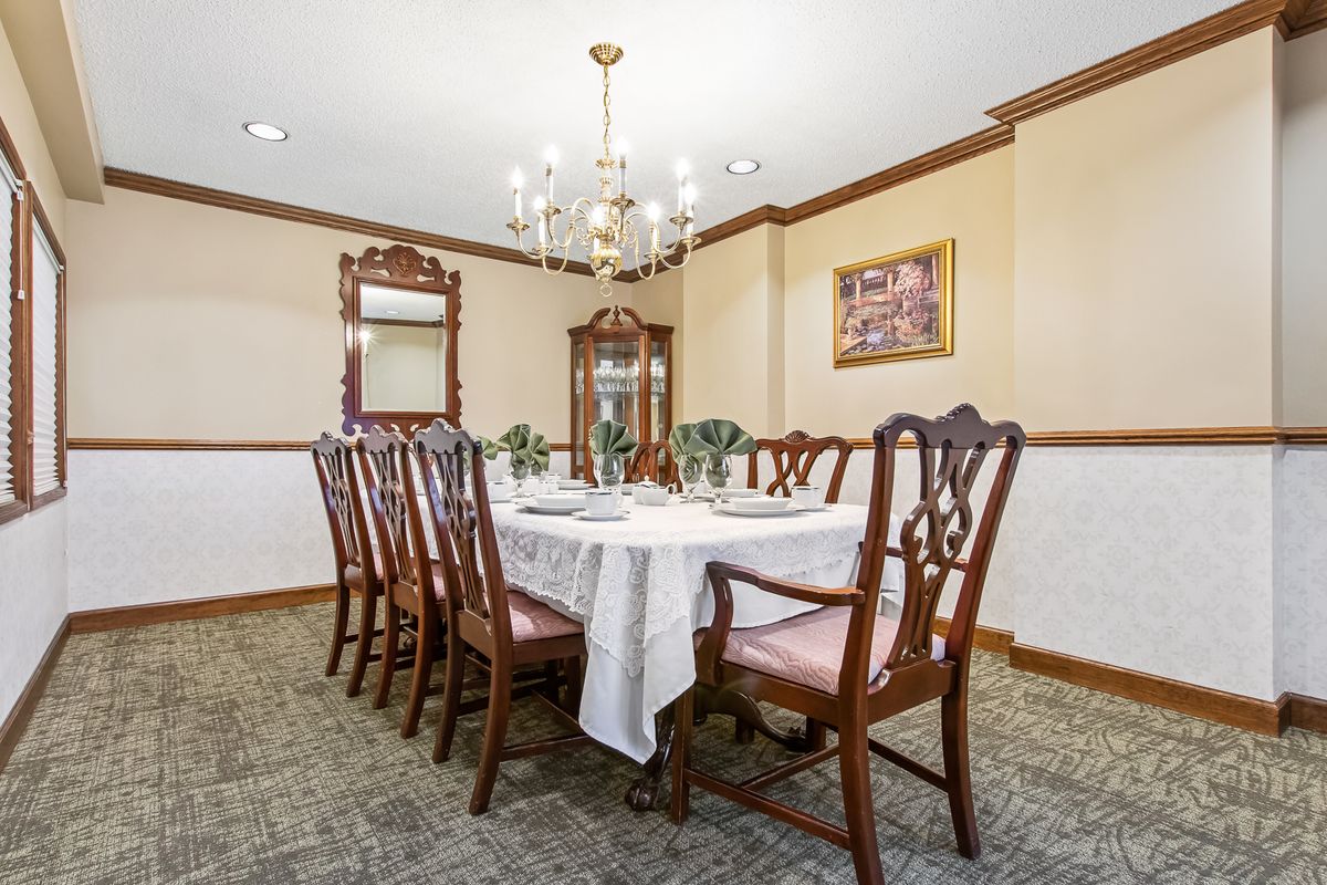 A traditional dining room with a set table, ornate chairs, and a chandelier.