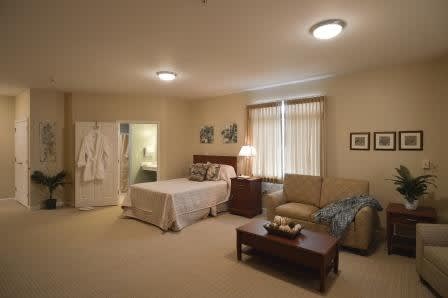 A cozy bedroom featuring a bed, sofa, and soft lighting with a warm color palette.