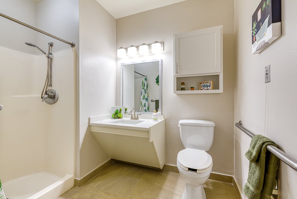 A modern and clean bathroom featuring a toilet, sink, mirror, and shower.