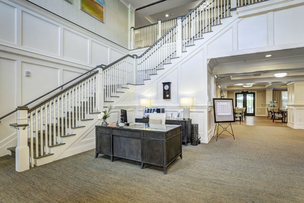 A spacious lobby featuring a grand staircase and a reception desk.