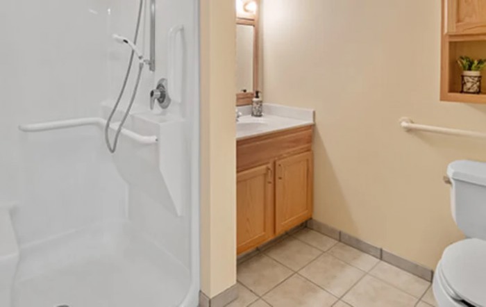 A clean bathroom featuring a shower and a wooden vanity with a sink and mirror.