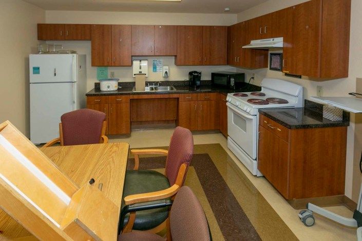 A kitchen with wooden cabinets, dining table, and standard appliances.