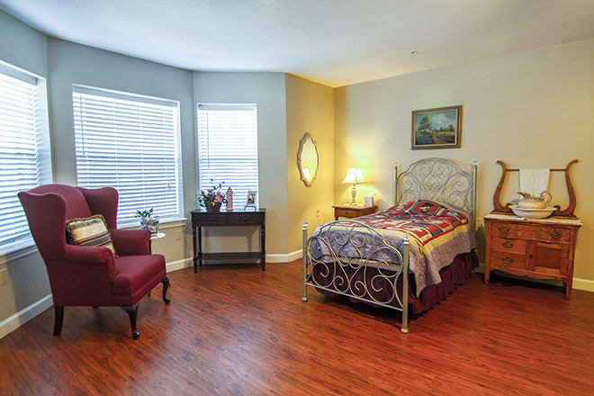 A cozy bedroom with a single bed, armchair, and warm lighting.
