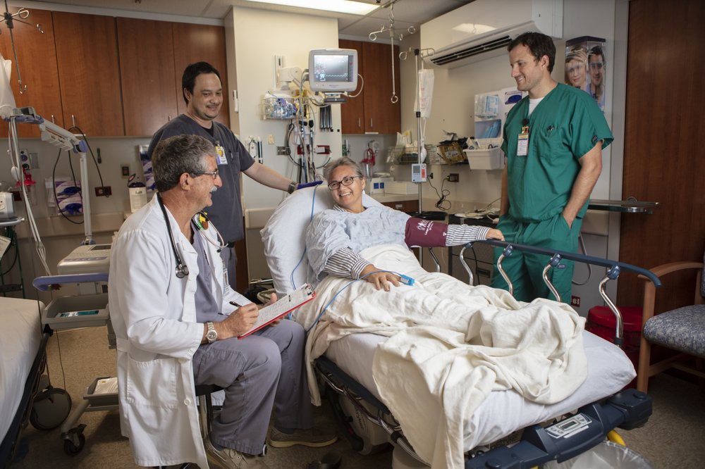 A group of medical professionals attending to a patient in a hospital room.