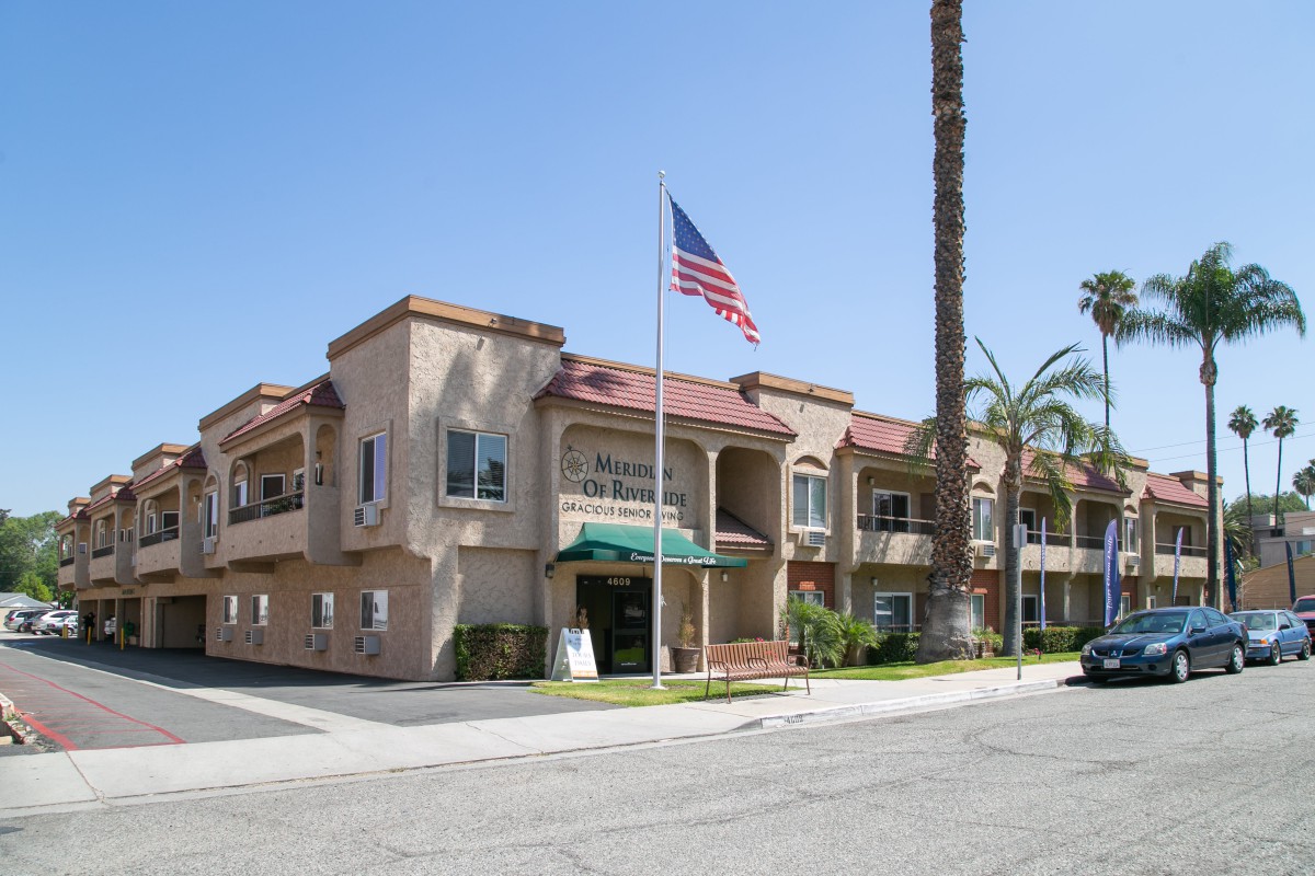 A sunny day at a residential or commercial building with an American flag and palm trees.