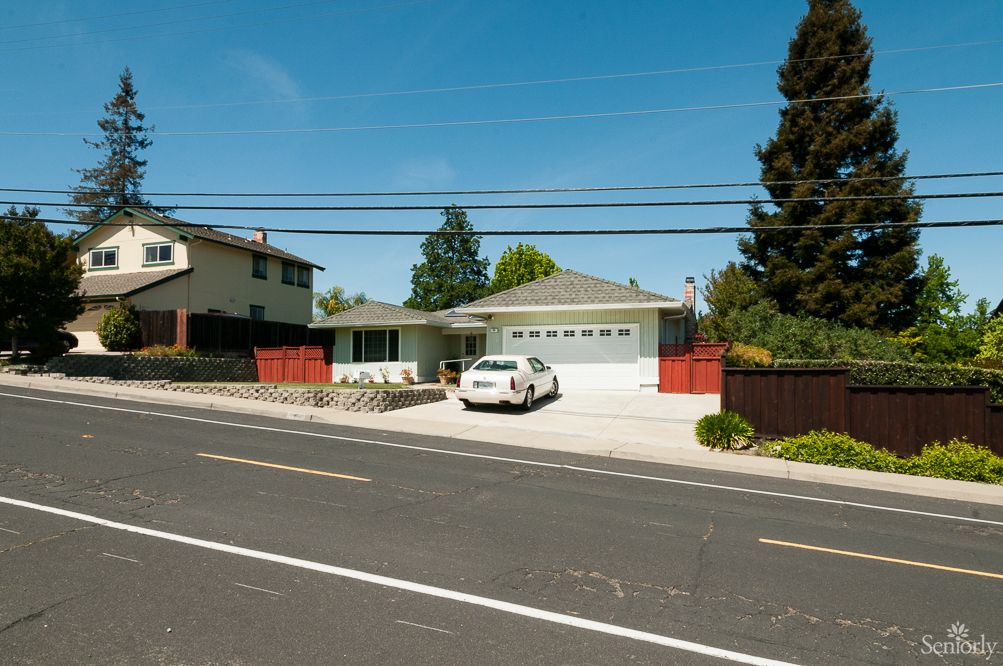 A suburban house with a car parked in the driveway on a clear day.