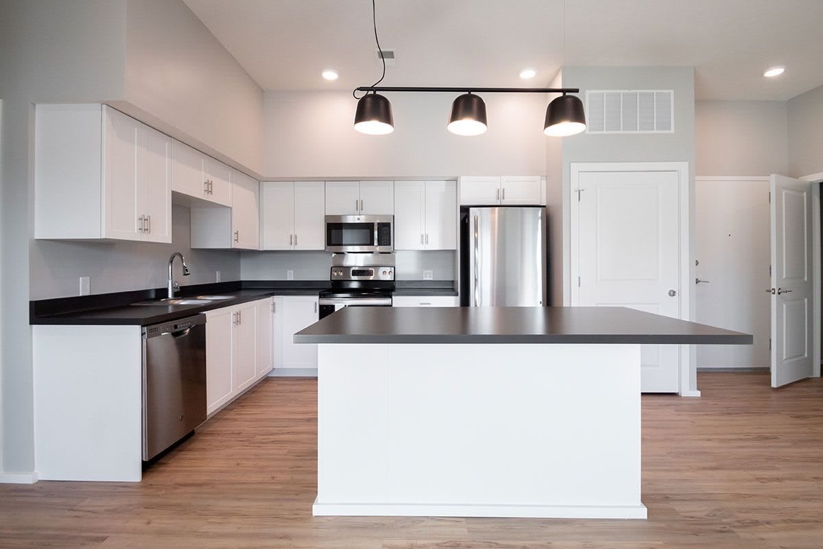 A modern kitchen with white cabinets, stainless steel appliances, and a central island with overhead lighting.