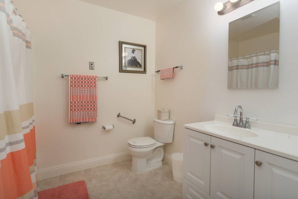 A clean and organized bathroom with a toilet, sink, mirror, and towels.