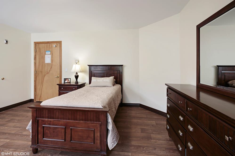 A cozy bedroom with a single wooden bed and matching dresser.