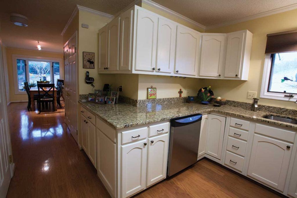 A modern kitchen with white cabinets, granite countertops, and a stainless steel dishwasher.